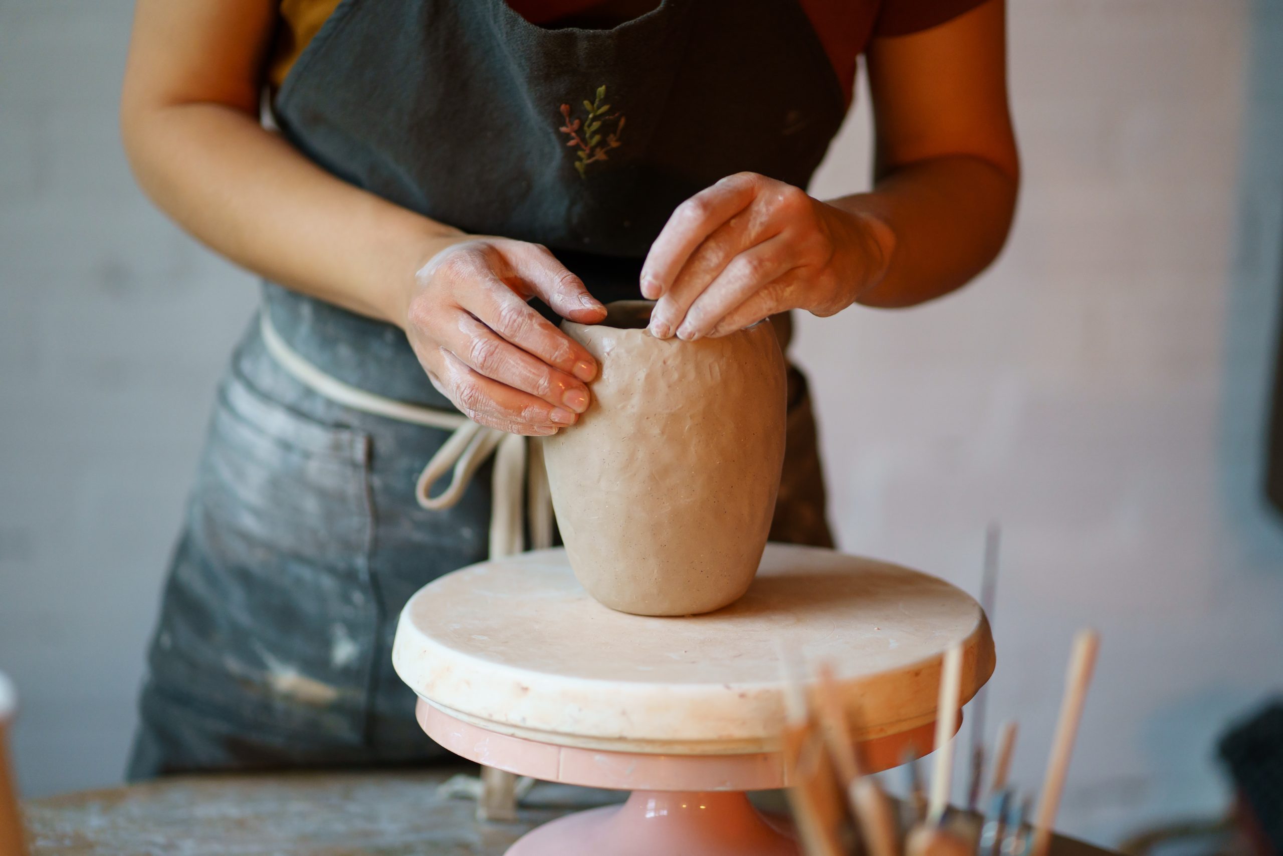 Focus on art and handicraft: cropped image of female concentrated sculpturing potter tableware in studio. Woman visit ceramics classes after work for stress relief and relax. Hobby and therapy concept