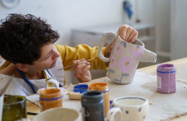 Art for hobby and recreation: young woman spent leisure after work at ceramic workshop relaxing while sculpturing and decorating pottery on handmade craftsmanship classes. Artistic therapy concept