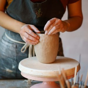 Ceramist female concentrated shaping potter jug in studio. Woman visit ceramics classes after work Focus on art and handicraft: cropped image of female concentrated sculpturing potter tableware in studio. Woman visit ceramics classes after work for stress relief and relax. Hobby and therapy concept