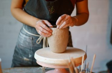 Focus on art and handicraft: cropped image of female concentrated sculpturing potter tableware in studio. Woman visit ceramics classes after work for stress relief and relax. Hobby and therapy concept