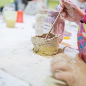 Closeup,Of,Childrens,Hands,Painting,With,Brush,Clay,Items,At